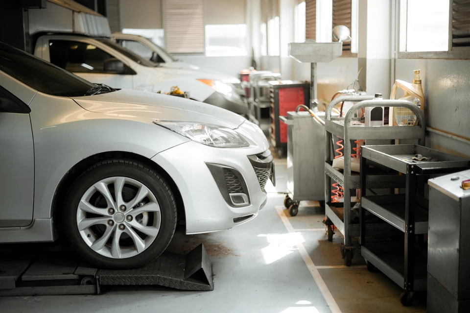 Atelier de réparation automobile moderne avec véhicule argenté surélevé sur pont élévateur