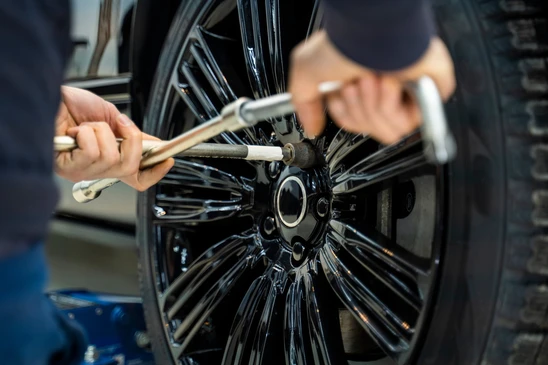 Intérieur d'un atelier automobile, mécanicien utilisant une clé dynamométrique pour serrer les boulons de roue d'un véhicule